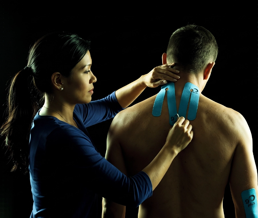 Fisioterapeuta profesional aplicando cinta kinesiológica Go Plus a un paciente